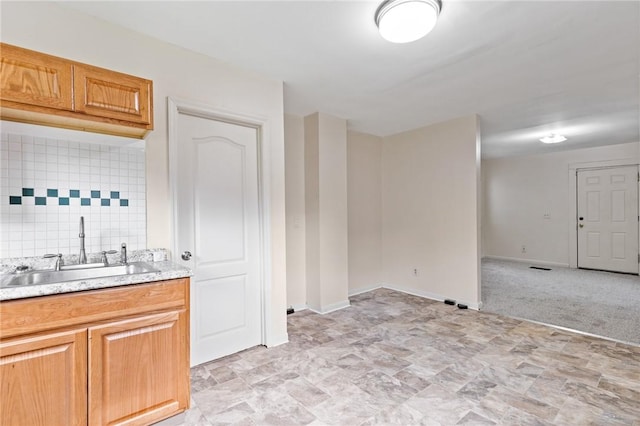 kitchen with a sink, light countertops, and baseboards