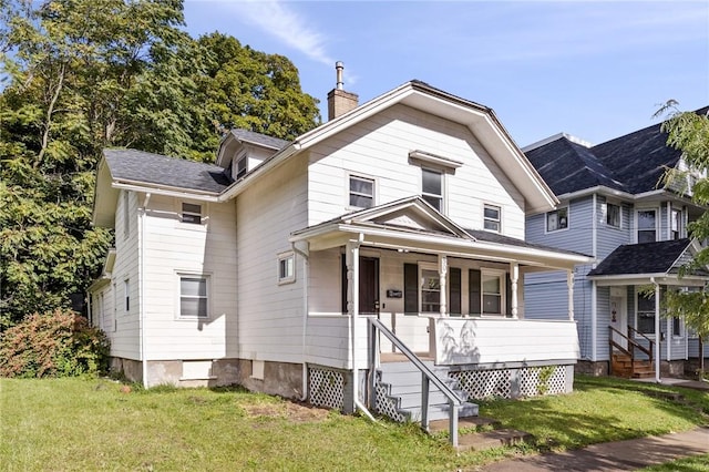 view of front of house featuring a chimney, a front lawn, and covered porch