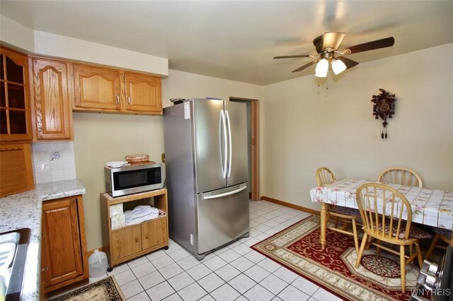 150 Leonard St, Lackawanna, NY 14218 - kitchen with appliances with stainless steel finishes, ceiling fan, glass insert cabinets, tasteful backsplash, and light stone counters