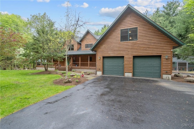 chalet / cabin with a front yard, asphalt driveway, covered porch, and faux log siding