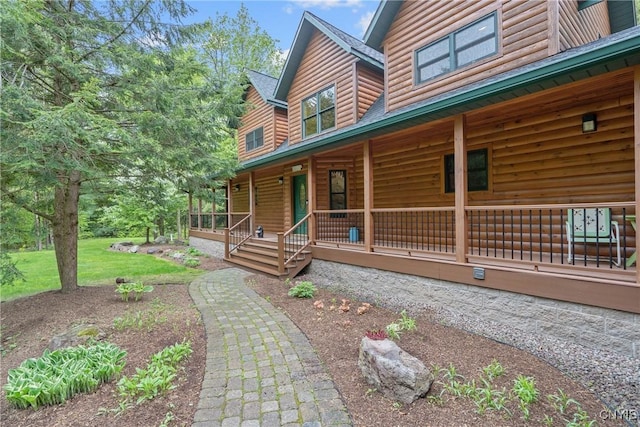 view of property exterior with faux log siding and covered porch