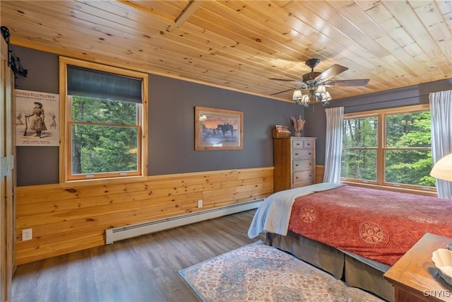 bedroom featuring baseboard heating, wooden ceiling, multiple windows, wood finished floors, and wood walls
