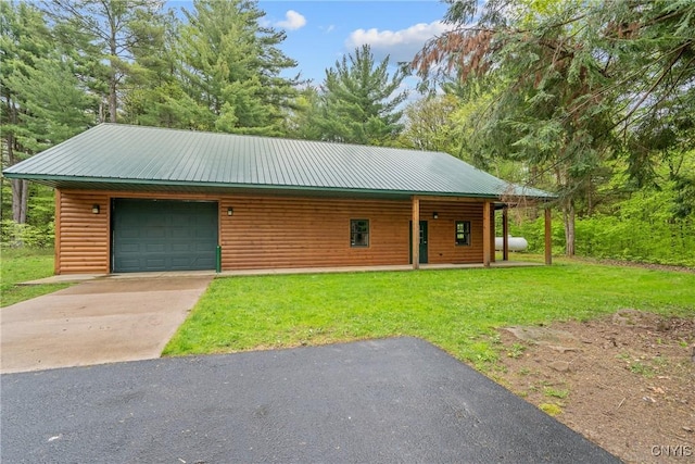 view of front of home with faux log siding, a front lawn, concrete driveway, a garage, and metal roof