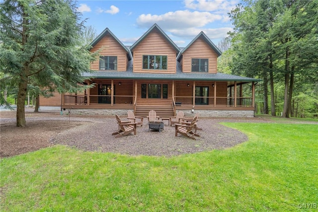 rear view of property with an outdoor fire pit, a lawn, covered porch, and faux log siding