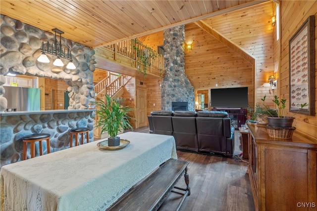dining space featuring wood ceiling, wood finished floors, stairs, wooden walls, and a towering ceiling