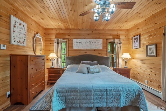 bedroom with wood finished floors, wooden walls, wooden ceiling, a baseboard heating unit, and ceiling fan