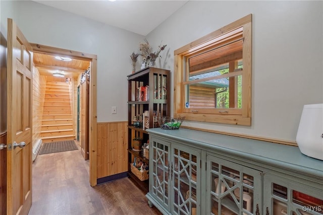 hall with wood finished floors, wooden walls, and a wainscoted wall
