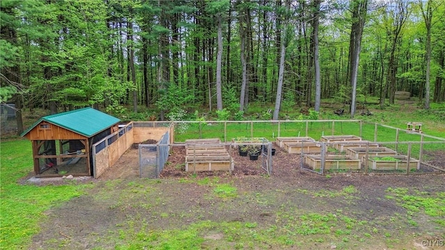 view of yard featuring a vegetable garden, exterior structure, an outbuilding, and fence