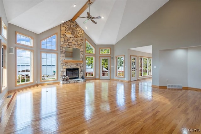 7179 Lakeshore Rd, Cicero, NY 13039 - unfurnished living room featuring high vaulted ceiling, light wood finished floors, a ceiling fan, a stone fireplace, and beam ceiling