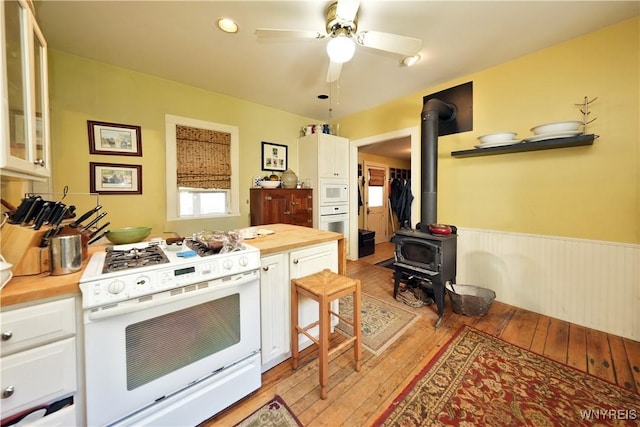 5195 Genesee Rd, North Collins, NY 14141 - kitchen with white appliances, butcher block counters, a wood stove, light wood-type flooring, and a wainscoted wall