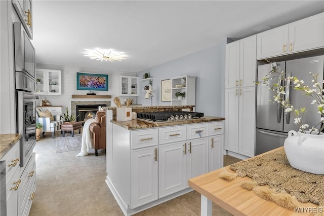 524 Pletcher Rd, Lewiston, NY 14092 - kitchen featuring appliances with stainless steel finishes, light stone counters, white cabinetry, a glass covered fireplace, and light colored carpet