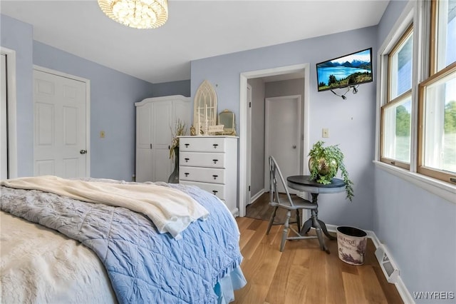 524 Pletcher Rd, Lewiston, NY 14092 - bedroom featuring multiple windows, light wood-style flooring, a chandelier, and baseboards