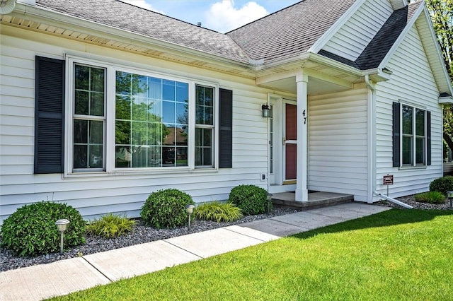 property entrance featuring roof with shingles and a lawn