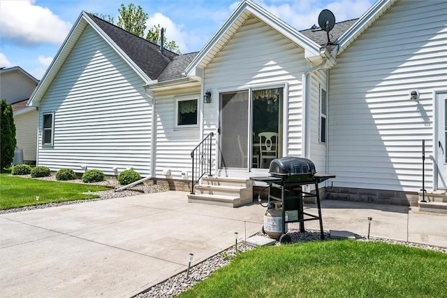 rear view of house featuring entry steps, a patio, and roof with shingles