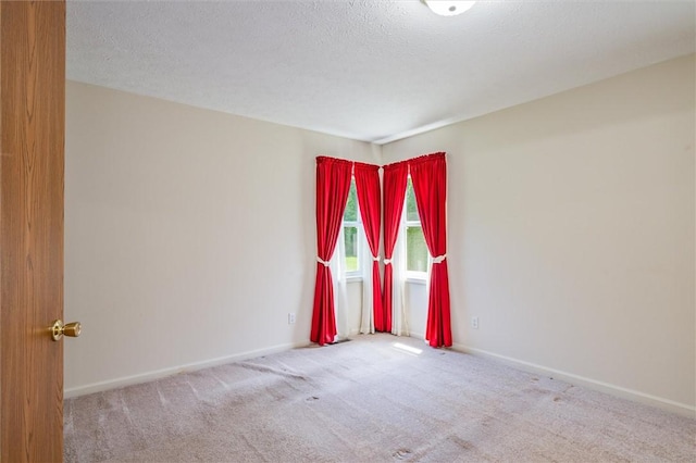 carpeted empty room featuring baseboards and a textured ceiling