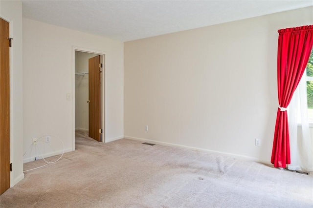 unfurnished bedroom featuring carpet, baseboards, and a walk in closet
