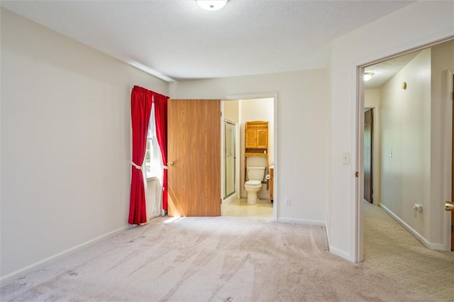 unfurnished bedroom featuring carpet floors, baseboards, and ensuite bathroom