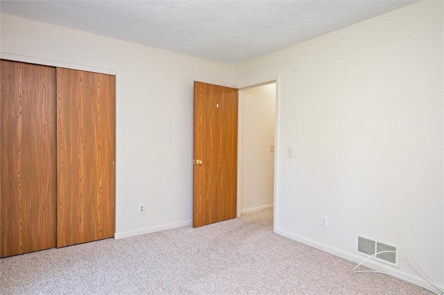 unfurnished bedroom featuring carpet floors, baseboards, a closet, and a textured ceiling