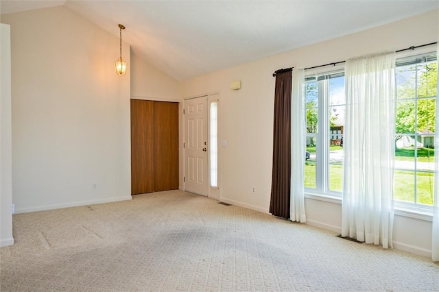 entrance foyer featuring light carpet, vaulted ceiling, healthy amount of natural light, and baseboards