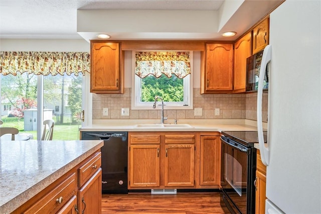 kitchen with black appliances, a sink, dark wood-type flooring, and plenty of natural light