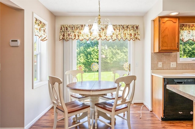 dining room featuring light wood-type flooring, healthy amount of natural light, and a chandelier