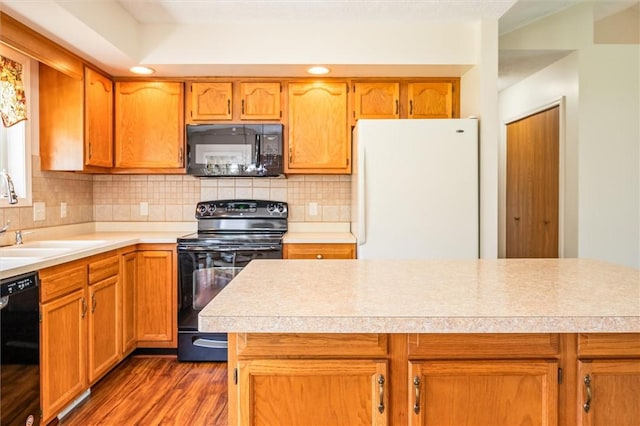 kitchen with black appliances, a sink, light countertops, tasteful backsplash, and recessed lighting