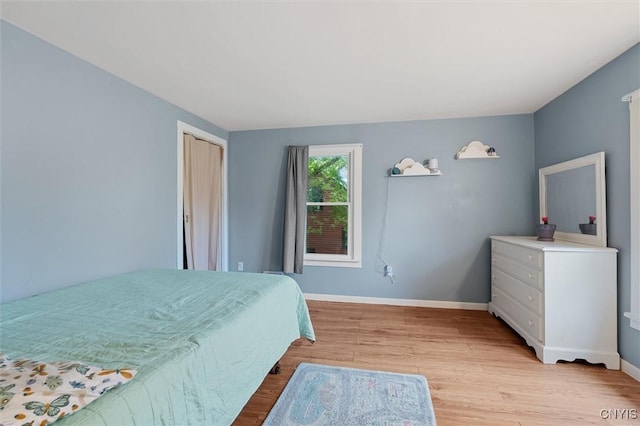 bedroom with light wood finished floors, baseboards, and a closet