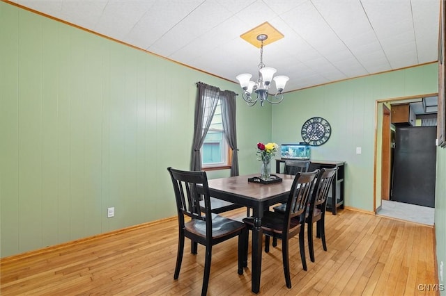 dining area featuring light wood finished floors, a chandelier, and ornamental molding