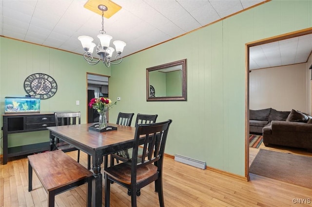 dining space with baseboard heating, a chandelier, light wood finished floors, and ornamental molding