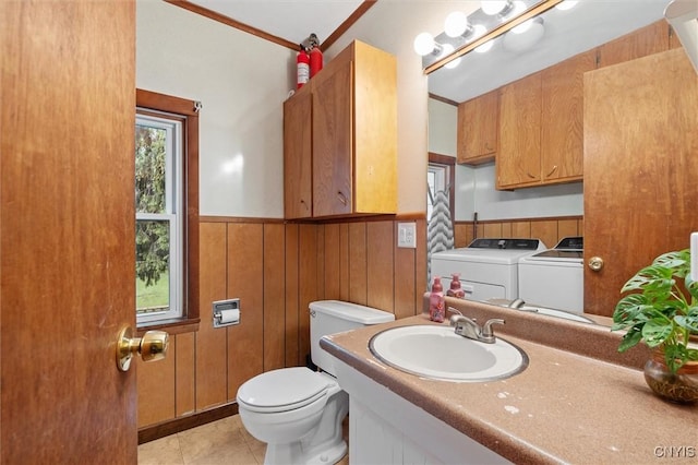 half bath with washing machine and clothes dryer, a wainscoted wall, toilet, tile patterned flooring, and vanity