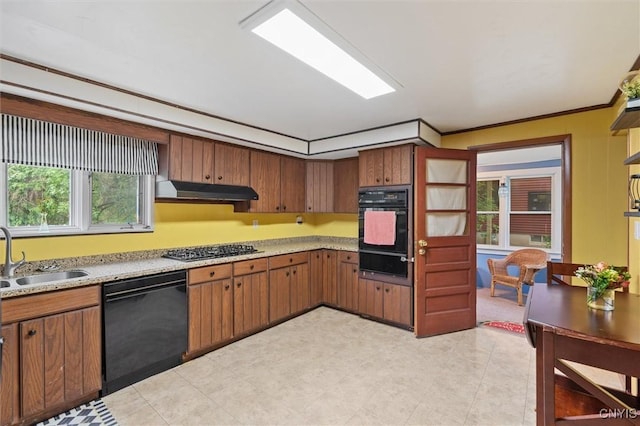 kitchen with black appliances, a sink, a warming drawer, under cabinet range hood, and light countertops