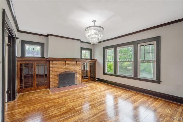 944 Bellevue Ave, Syracuse, NY 13204 - unfurnished living room with crown molding, light wood-style flooring, plenty of natural light, a chandelier, and a brick fireplace