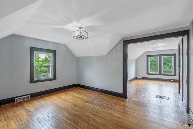 944 Bellevue Ave, Syracuse, NY 13204 - additional living space with a chandelier, lofted ceiling, plenty of natural light, wood-type flooring, and baseboards