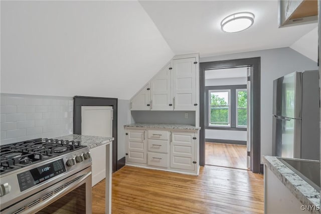 944 Bellevue Ave, Syracuse, NY 13204 - kitchen featuring appliances with stainless steel finishes, lofted ceiling, white cabinetry, light wood-style floors, and decorative backsplash