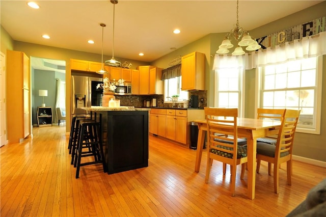 90 Davenport Rd, Big Flats, NY 14814 - kitchen with stainless steel appliances, a chandelier, light wood-type flooring, a kitchen bar, and decorative backsplash