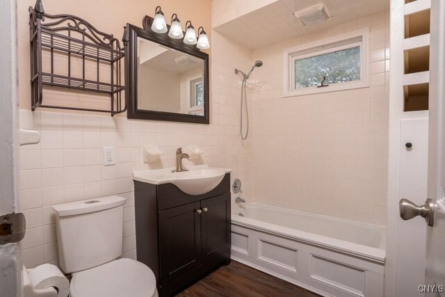 1628 Mohawk St, Utica, NY 13501 - bathroom featuring shower / washtub combination, toilet, wood finished floors, vanity, and tile walls