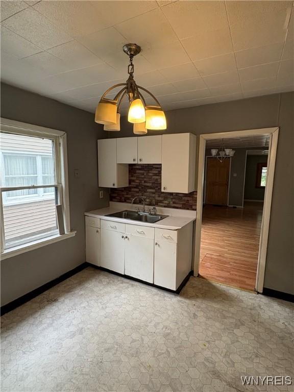 68 Decker St, Buffalo, NY 14215 - kitchen featuring a chandelier, white cabinetry, hanging light fixtures, light countertops, and backsplash