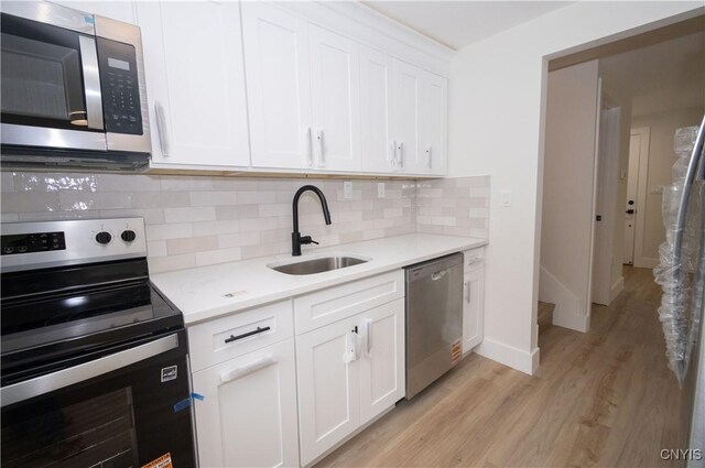 5646 Vistula, Cicero, NY 13029 - kitchen featuring appliances with stainless steel finishes, a sink, light wood finished floors, decorative backsplash, and white cabinets