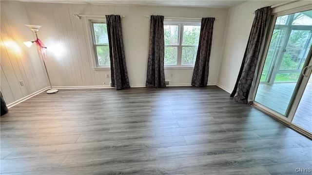unfurnished room with plenty of natural light, baseboards, and wood finished floors