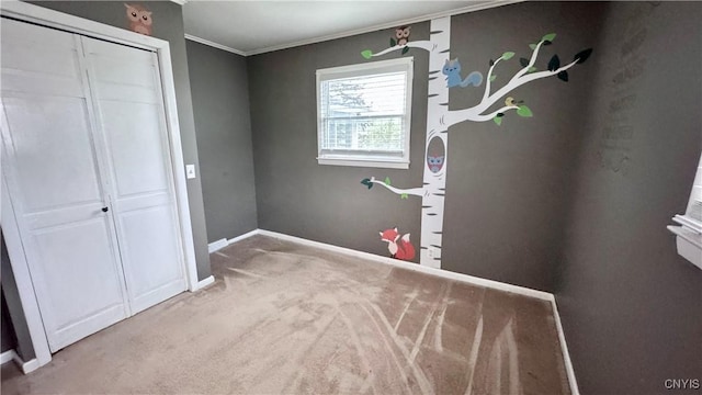 unfurnished bedroom with ornamental molding, carpet, baseboards, and a closet