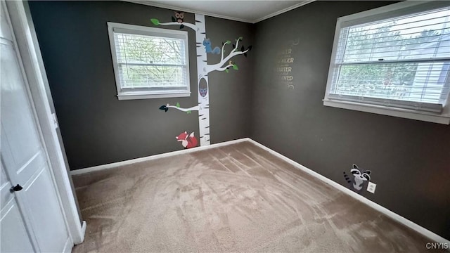 spare room with carpet flooring, ornamental molding, and baseboards