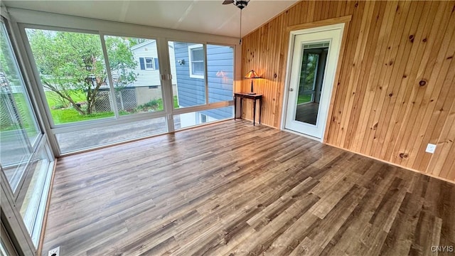 empty room with lofted ceiling, wooden walls, and wood finished floors