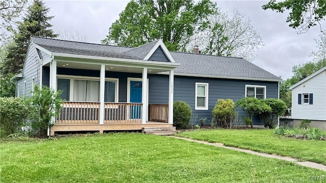 view of front of house with a front yard, a chimney, a porch, and roof with shingles