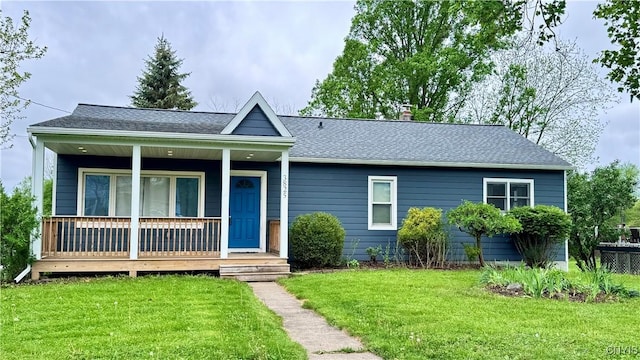 view of front facade with a front lawn, covered porch, and a shingled roof