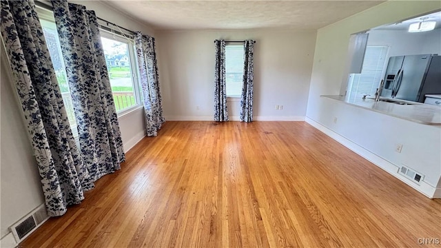 empty room with light wood-style flooring, a sink, and baseboards