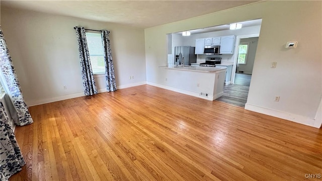 unfurnished living room featuring light wood-type flooring and baseboards