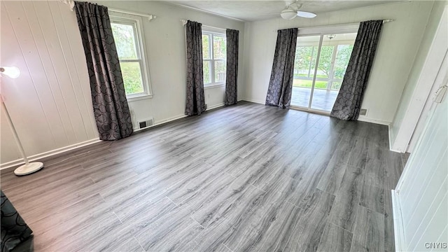 empty room featuring healthy amount of natural light, wood finished floors, and baseboards