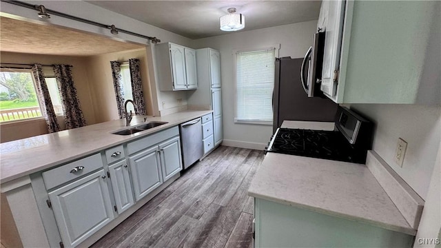 kitchen with appliances with stainless steel finishes, a sink, plenty of natural light, and light countertops
