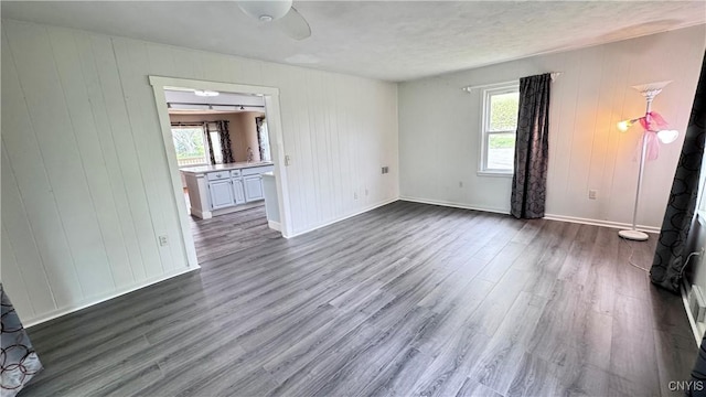 spare room featuring dark wood-style floors, wood walls, and baseboards