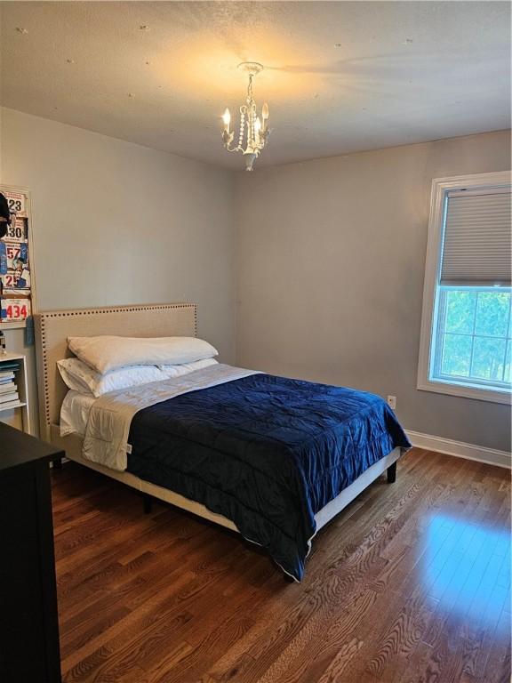 1 Woodsview Dr, Big Flats, NY 14903 - bedroom with dark wood-type flooring, a chandelier, and baseboards